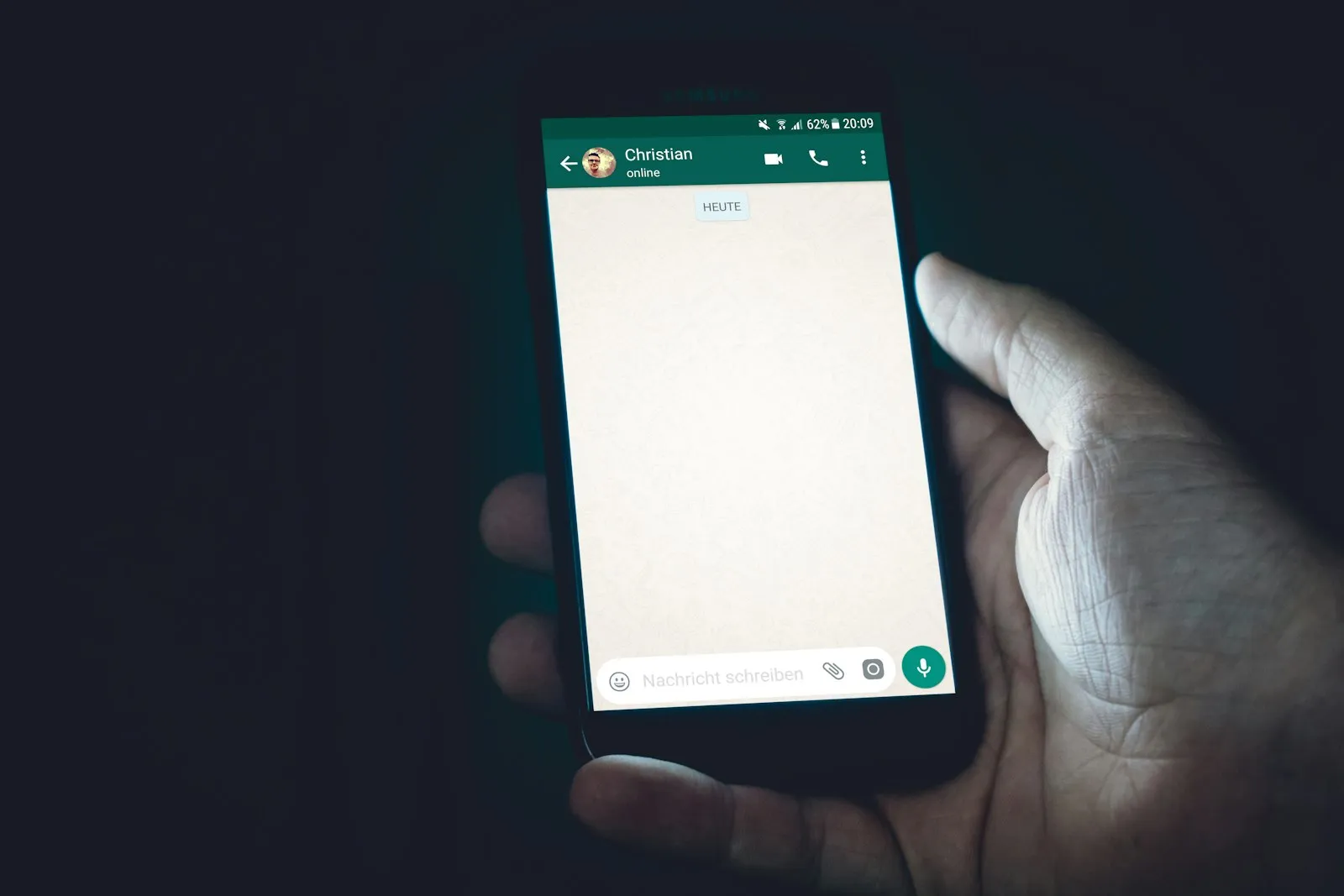 Mão segurando um celular com uma conversa de WhatsApp aberta