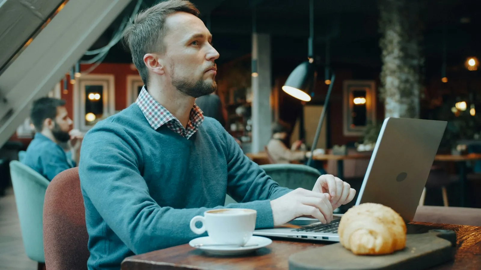 Homem trabalhando em um notebook em uma cafeteria