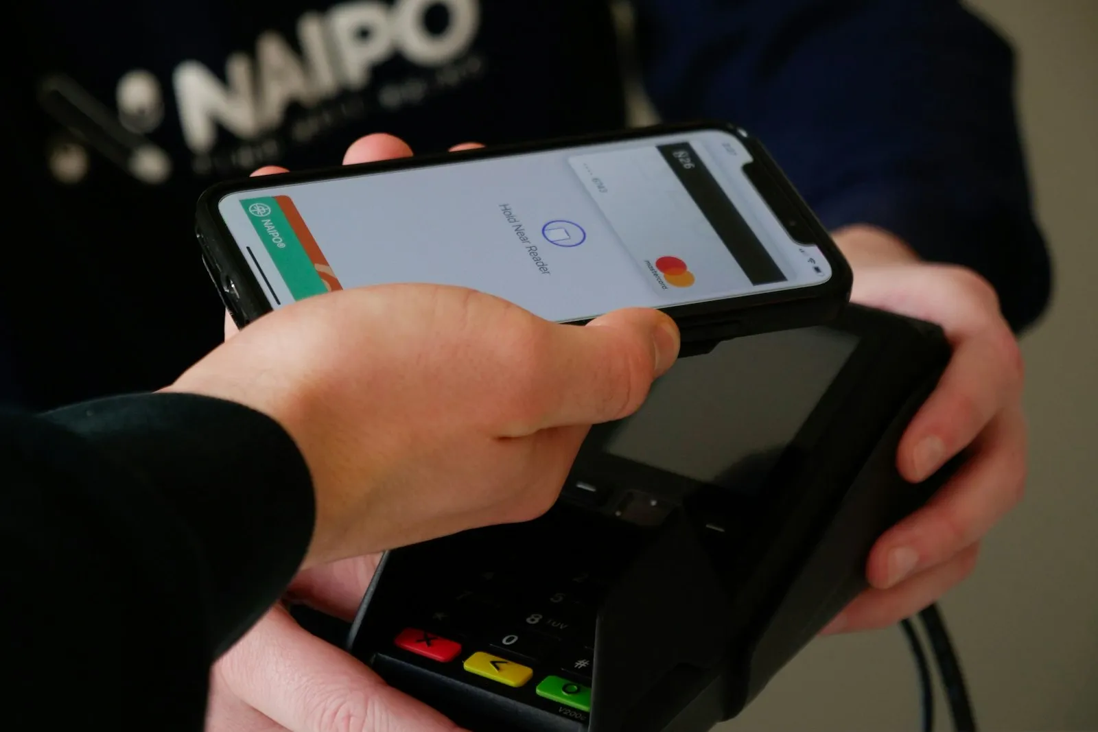 Pessoa pagando com o celular em uma maquininha de cartão