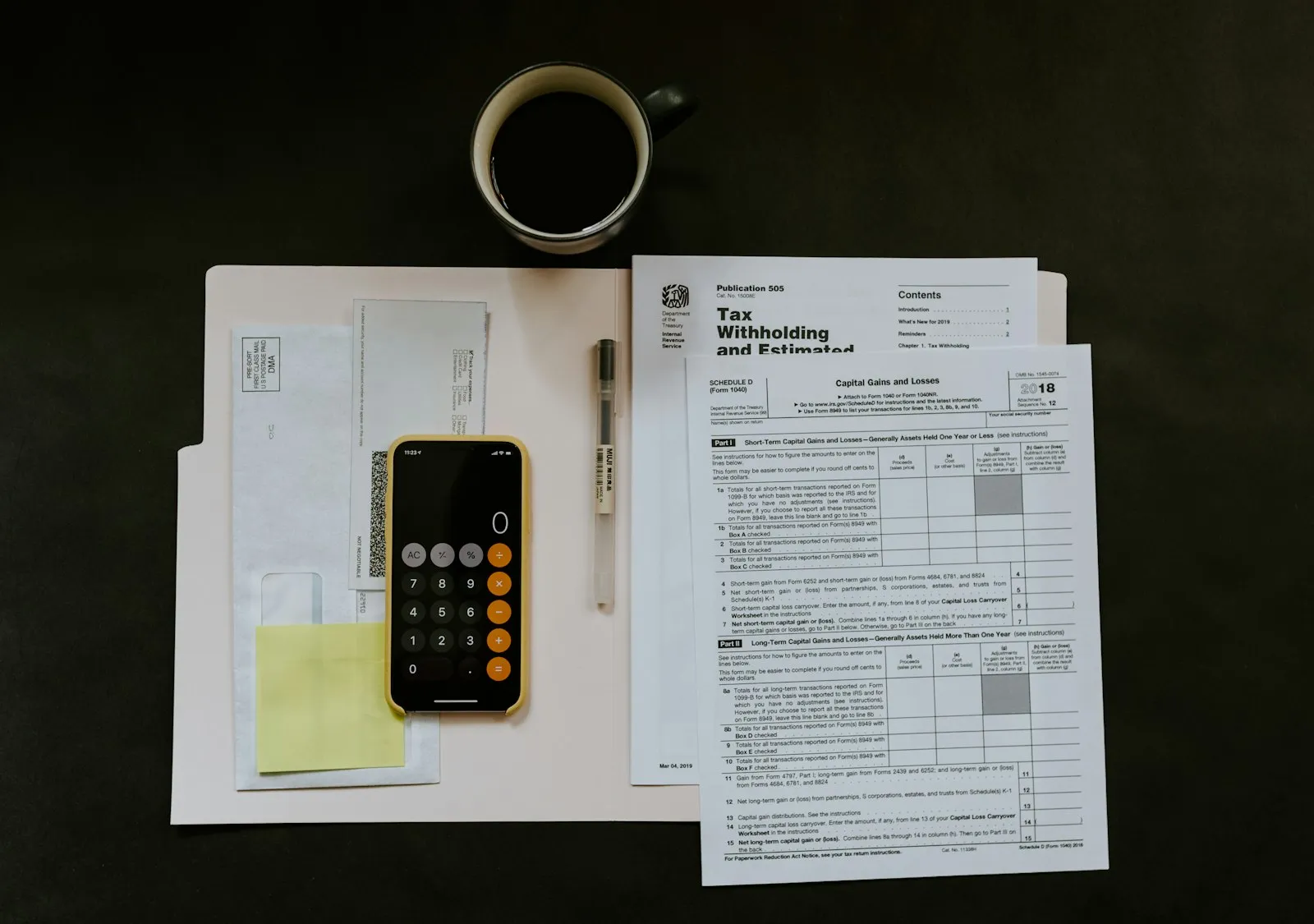 Formulários fiscais, calculadora e café sobre uma mesa escura