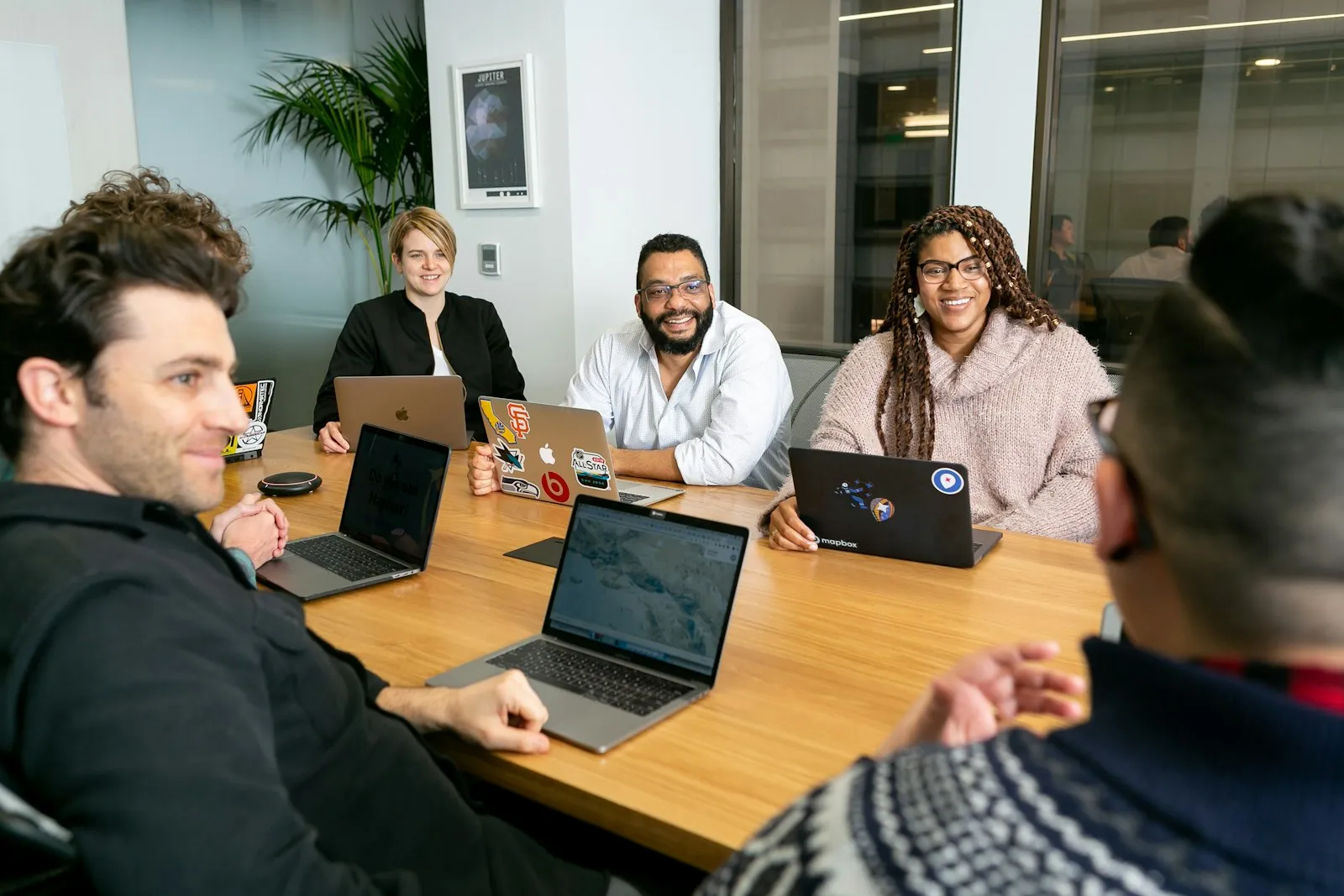 Equipe reunida em volta de uma mesa com notebooks discutindo um projeto
