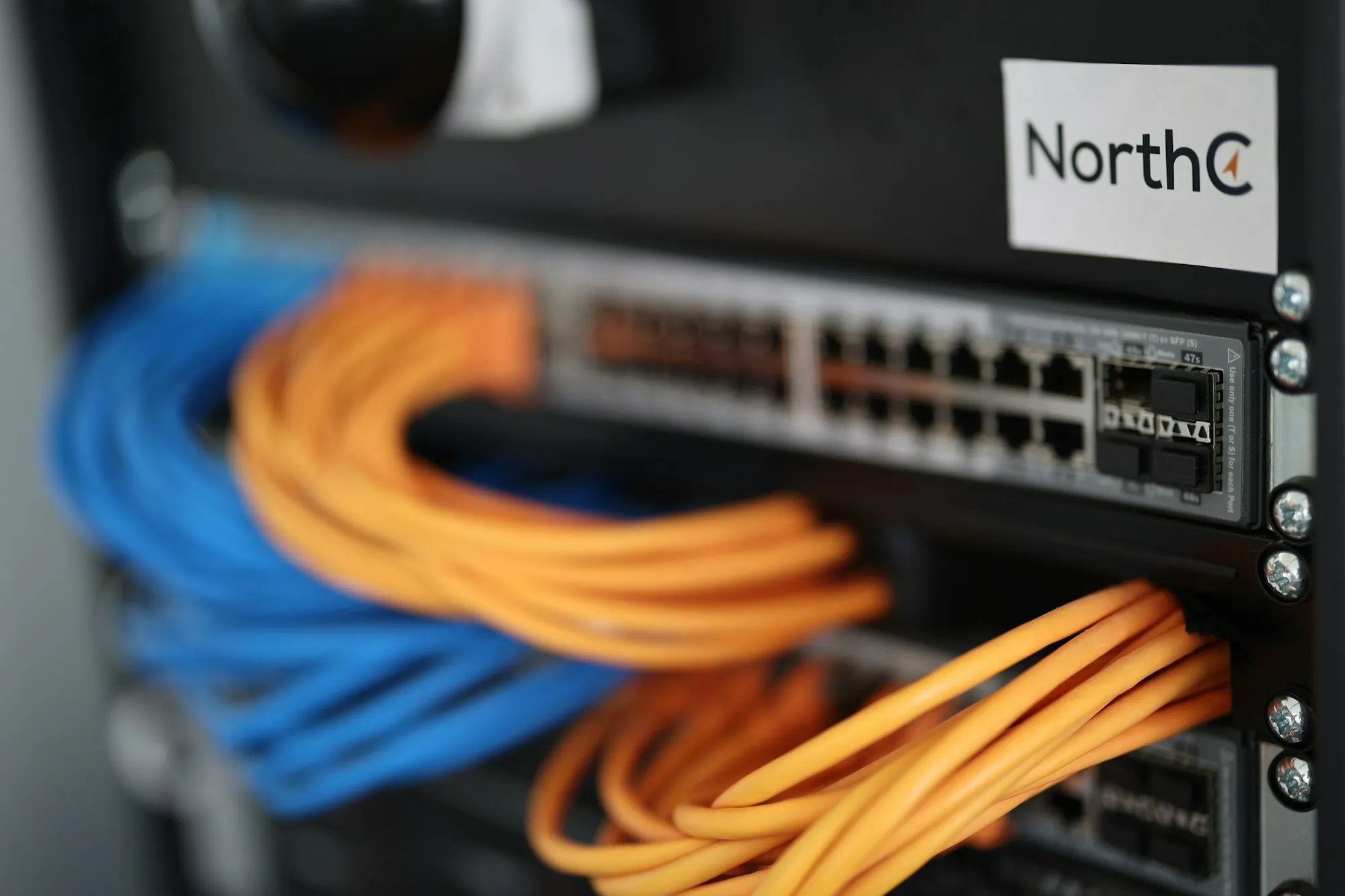 Switch de rede em rack com cabos azuis e laranjas conectados
